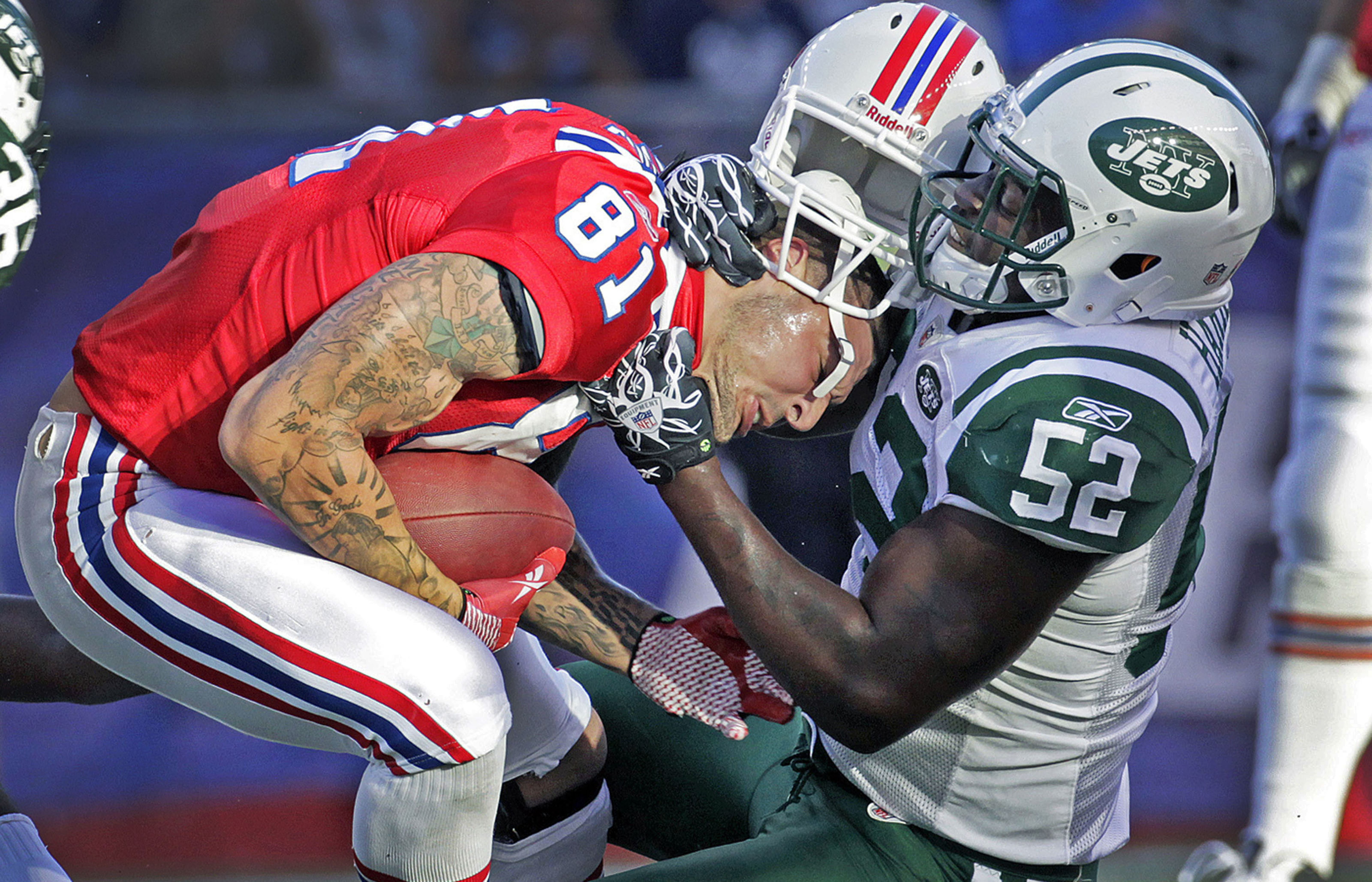 Patriots tight end Aaron Hernandez (left) is taken down by the Jets David Harris after a first quarter catch, and he loses his helmet in the process. The New England Patriots hosted the New York Jets in a regular season NFL game at Gillette Stadium. Photo by Jim Davis for the Boston Globe. Courtesy of The Boston Globe