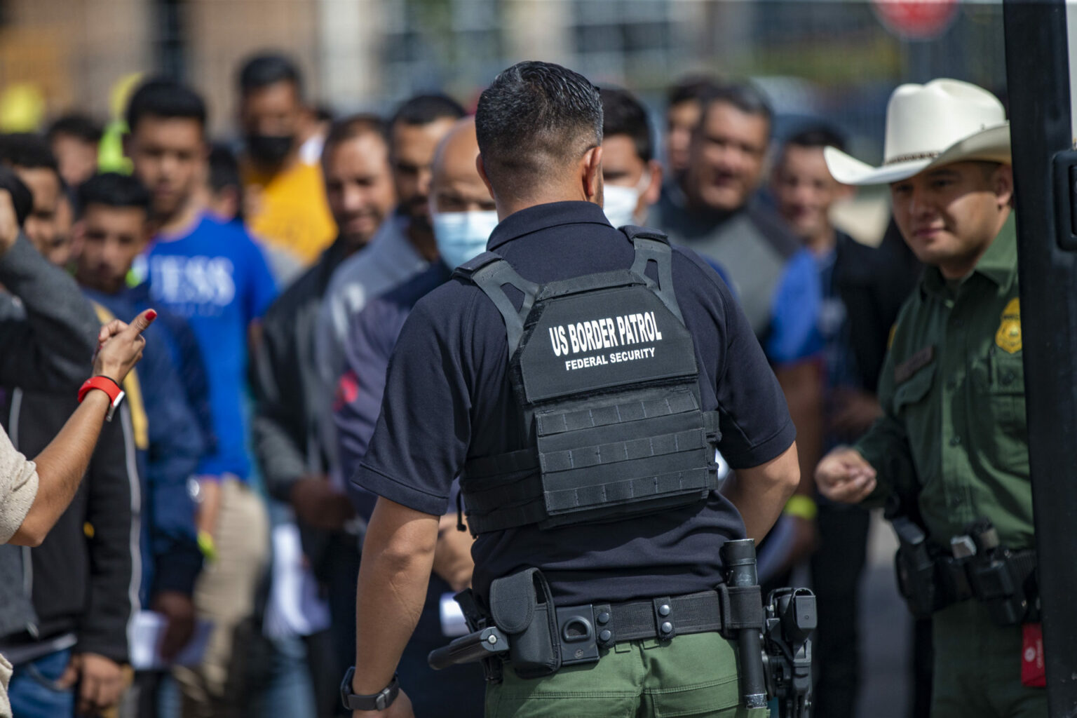 A U.S. Border Patrol agent watches as immigrants line up to be processed at after being picked up at the U.S-Mexico border at the Immigration Welcome Center in El Paso.