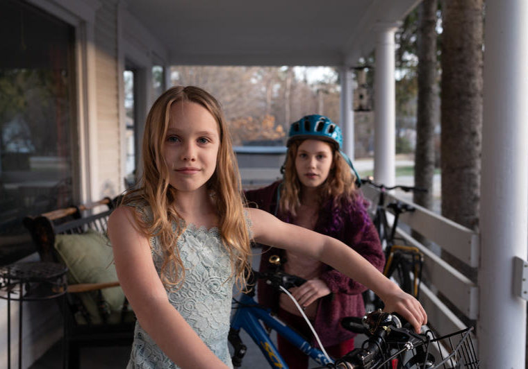 Morgan family portrait Azalea Morgan, 9, (left) and her sister Ember Morgan, 10 (right) stand with their bikes on the porch of their home in Andover, New Hampshire. The sisters biked to New York City from Andover with their mom to raise awareness of climate change in 2019. (Ryan Caron King/Connecticut Public/New England News Collaborative)